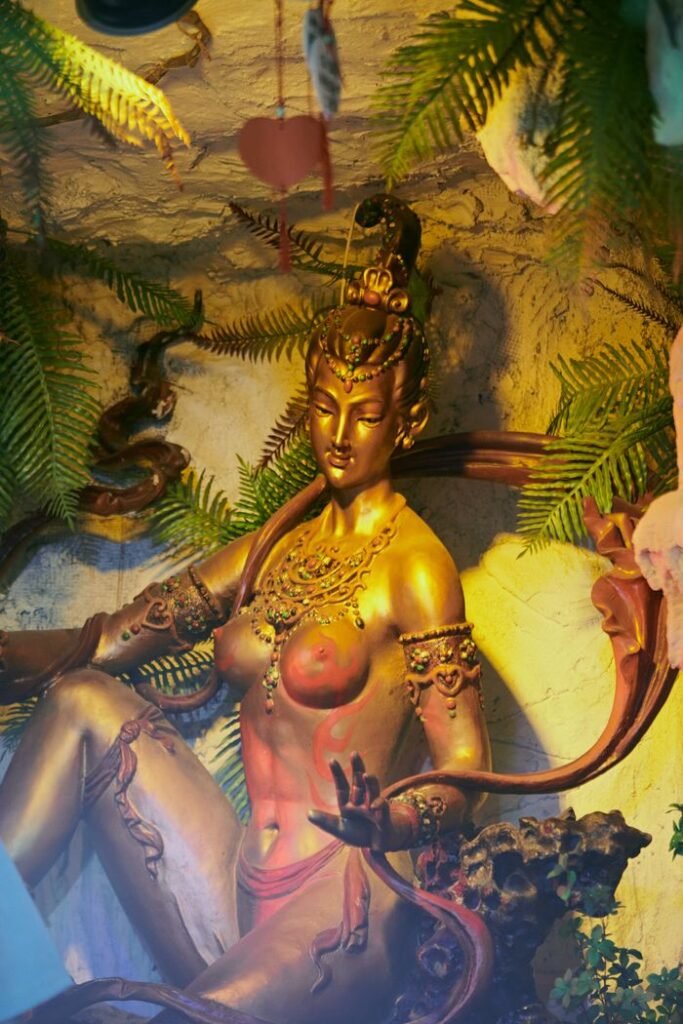 Elegant golden goddess statue surrounded by vibrant ferns, embodying spirituality and mythology.
