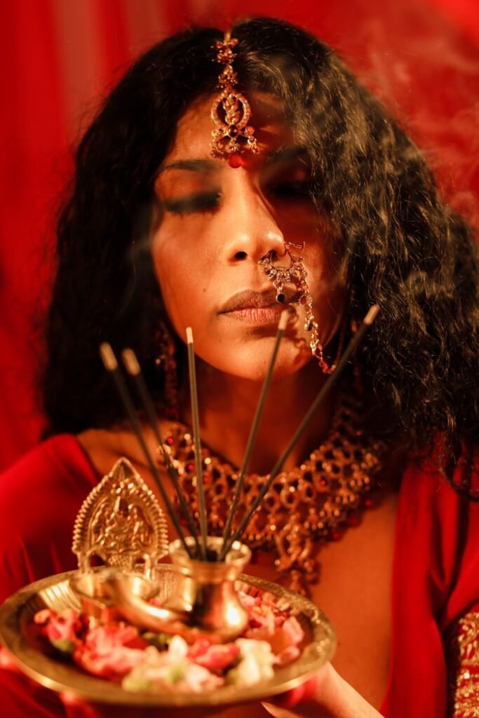 A woman in traditional attire holding an incense offering plate during a cultural ritual.