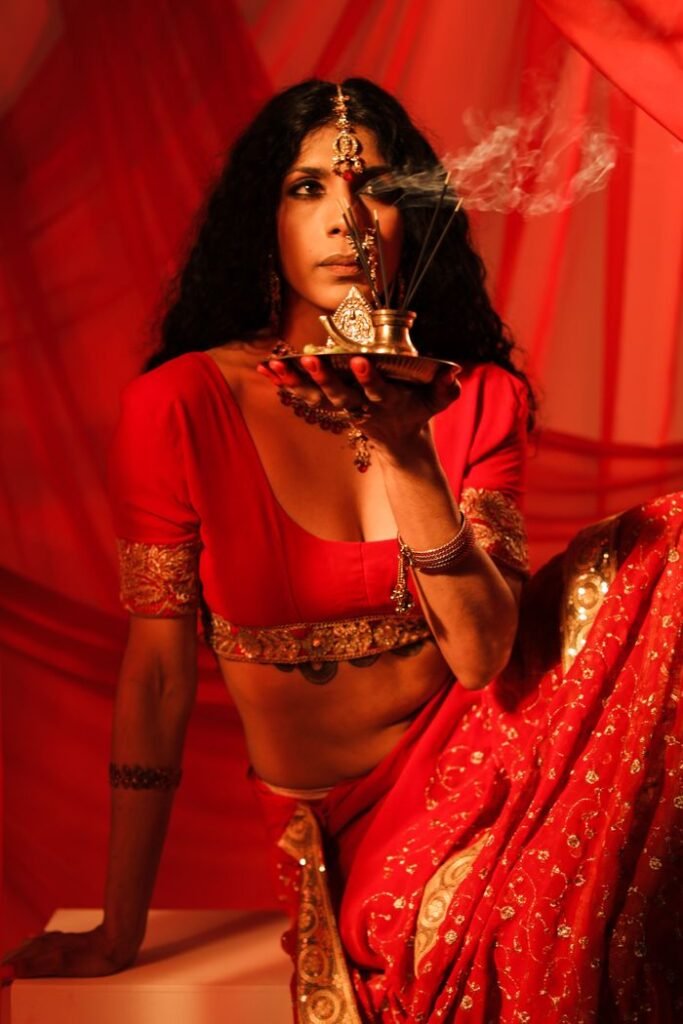 Stunning portrait of a woman in a red Indian sari holding incense, exuding elegance and cultural richness.